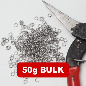 Op de afbeelding: Een stapel kleine, zilveren sprongringen met een tang. De tang heeft rode handvatten. Een rode rechthoek met de tekst "50g BULK" staat onderaan de afbeelding. De achtergrond is wit.