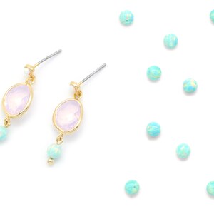 Könnte beinhalten: Ein Paar Ohrringe mit einem hellvioletten, ovalen Stein und einer hellblauen Perle, die an jedem Ohrring baumelt.