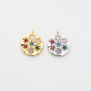 May include: Two round pendants with a hammered texture and a cluster of colorful gemstones in the center. The pendant on the left is gold-toned and the pendant on the right is silver-toned.