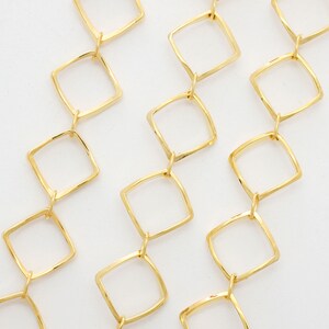 May include: Gold chain necklace with a square link design. The chain is made of multiple strands of linked squares.