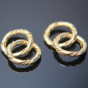 以下が含まれることがあります： ねじれたデザインの、金色のインターロッキングリングが2つ