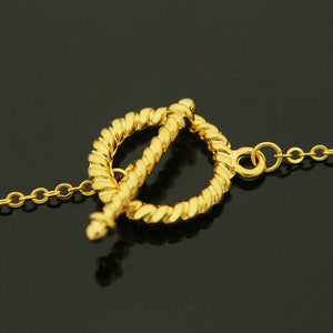 Puede incluir: Un collar de cadena de oro con un cierre de estilo cuerda trenzada. El cierre es un c&iacute;rculo con un c&iacute;rculo m&aacute;s peque&ntilde;o que se desliza a trav&eacute;s de &eacute;l.