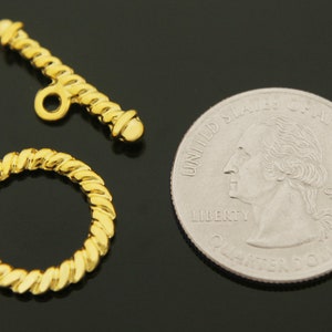 Puede incluir: Cierre de bot&oacute;n de metal dorado con un dise&ntilde;o de cuerda. El cierre es aproximadamente del tama&ntilde;o de una moneda de 25 centavos de d&oacute;lar estadounidense.