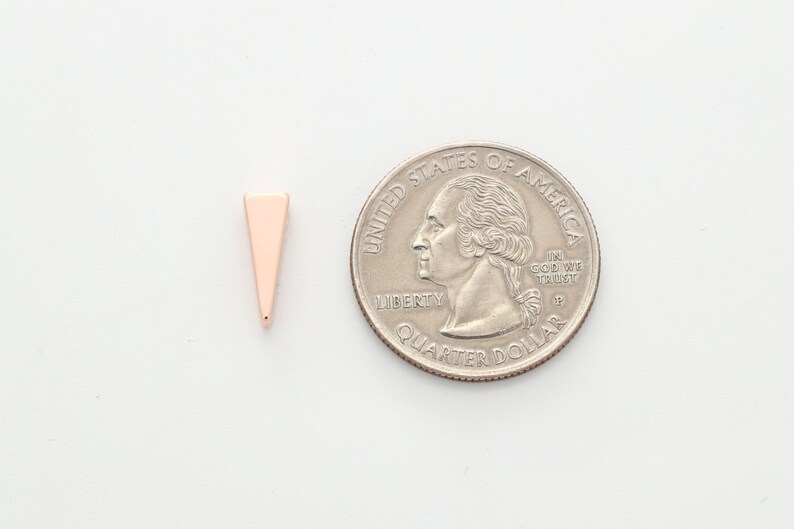 May include: A small, rose gold triangle charm, approximately the size of a US quarter.