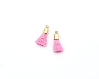 May include: Two pink tassel charms with gold metal tops.