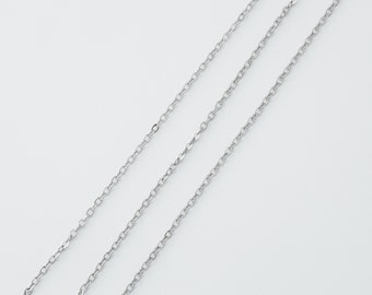 May include: Three delicate silver-colored chain necklaces are arranged diagonally across a white background. The chains are made of small, interconnected links, creating a subtle, elegant texture. The chains are likely for jewelry.