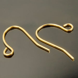 以下が含まれることがあります： 曲線状のワイヤーと端部に小さなループが付いた、金色のイヤリングフックが2つです。