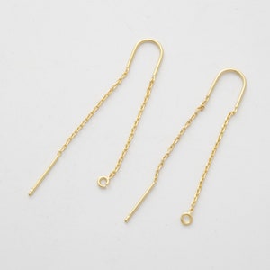 Puede incluir: Un par de cierres de pendientes dorados con una cadena y un pequeño bucle en el extremo.