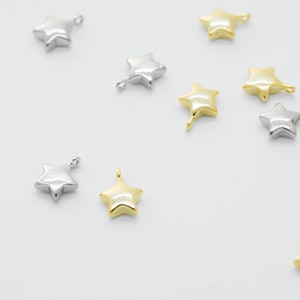 Puede incluir: Una colección de abalorios en forma de estrella de color dorado y plateado con un bucle para sujetar a joyas u otras manualidades.