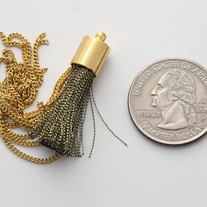 May include: A gold tassel with a green and black fringe and a gold chain.