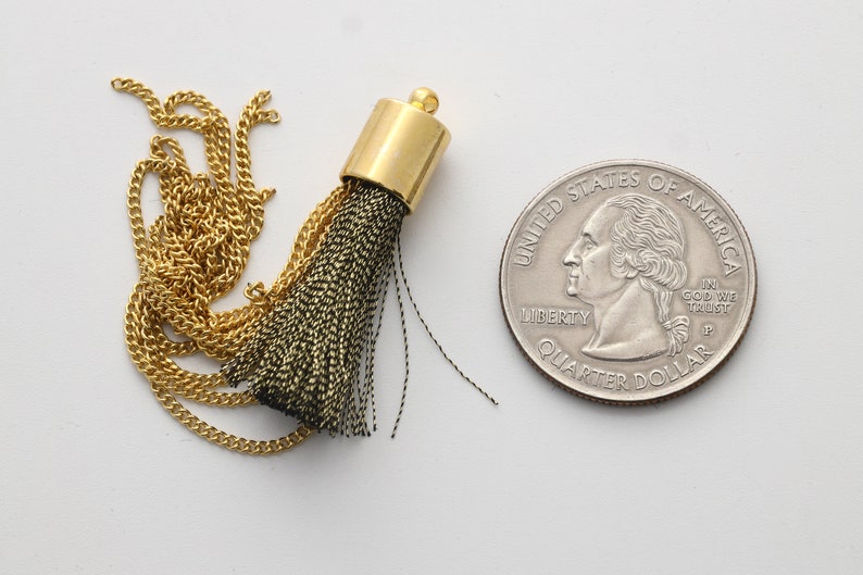 May include: A gold tassel with a green and black fringe and a gold chain.