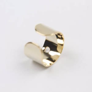 Könnte beinhalten: Ein goldfarbener Metallring mit einem einfachen, offenen Design. Der Ring ist aus glattem, poliertem Metall gefertigt und hat eine leicht abgerundete Form.