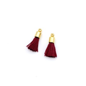 May include: Two small burgundy tassels with gold metal tops.