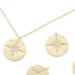 May include: A gold chain necklace with a compass pendant featuring a sparkling diamond-like star design. The pendant is surrounded by the letters N, S, E, and W.