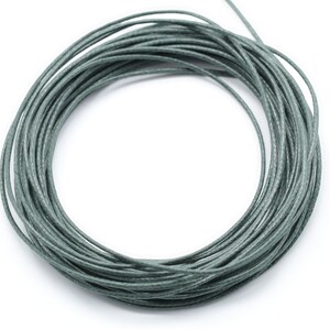 May include: A spool of sage green waxed cotton cord. The cord is wound tightly in a circle.