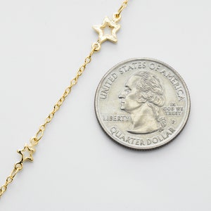 May include: A gold chain necklace with a delicate star charm. The necklace is shown next to a US quarter for size reference.