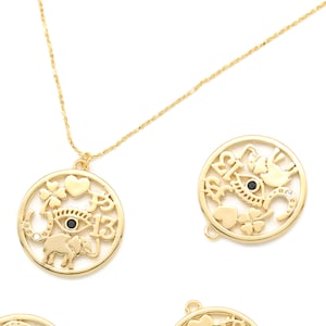 May include: Gold-colored necklace with a round pendant featuring an eye, elephant, heart, four-leaf clover, and the number 13. The pendant is surrounded by a circular frame. Additional gold pendants with similar designs are scattered around.