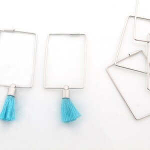 May include: A pair of silver hoop earrings with a turquoise tassel hanging from each hoop.