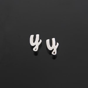 May include: A pair of silver earrings with the letter "Y" in a cursive font.