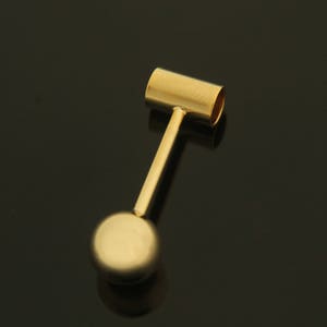 Peut inclure: Un pendentif en métal doré avec une boule ronde au bas et un dessus cylindrique.