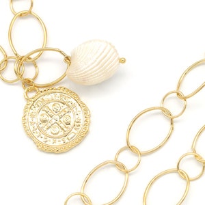 May include: Gold chain necklace with a large oval link design. The necklace has a charm with a religious symbol and a white shell charm.