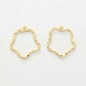 Puede incluir: Dos blanks para pendientes de metal de color dorado en forma de estrella ondulada. Los blanks tienen un peque&ntilde;o bucle en la parte superior para sujetar los hilos de los pendientes.