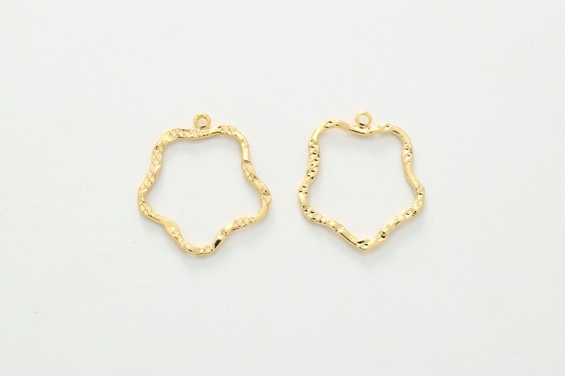 Puede incluir: Dos blanks para pendientes de metal de color dorado en forma de estrella ondulada. Los blanks tienen un peque&ntilde;o bucle en la parte superior para sujetar los hilos de los pendientes.