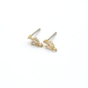 Puede incluir: Un par de pendientes de oro con pequeñas piedras transparentes en forma de baguette. Los pendientes tienen un diseño simple y minimalista.