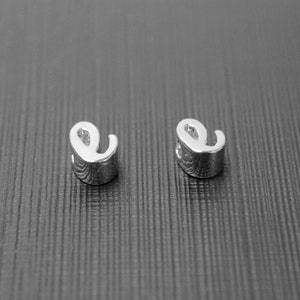 May include: A pair of silver letter 'e' earrings. The earrings are small and delicate, and they are perfect for everyday wear.