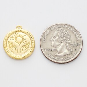 May include: Gold-toned pendant charm featuring a sun and two hands reaching up. The charm is about the size of a US quarter.