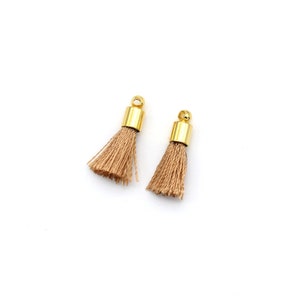 May include: Two small brown tassels with gold metal tops. The tassels are made of soft, fluffy fibres.