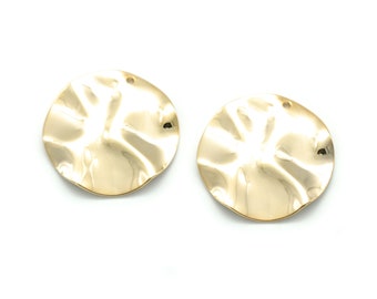 May include: Two gold-toned metal earrings with a textured, wavy surface. The earrings are round and have a hole at the top for attaching to a hook.