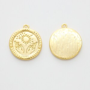 May include: Gold-toned metal pendant charm with a sun and two hands design on one side and a textured surface on the other side.