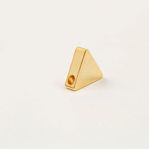May include: A gold triangle-shaped pendant with a hole in the centre for stringing.