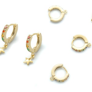 May include: Six gold hoop earrings with colorful stones. Two of the earrings have a star charm hanging from them.