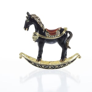 May include: A black rocking horse figurine with a gold base and saddle. The horse has a red saddle with gold accents and a green eye.