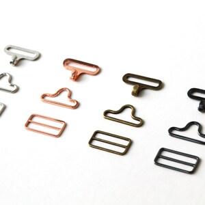 May include: Four sets of metal clasps for sewing projects. Each set includes a hook and a slider. The clasps are available in silver, rose gold, brass, and black.