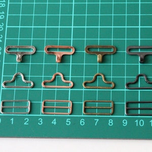 May include: Four sets of metal clasps in silver, copper, gold, and black. Each set includes three different styles: a T-shaped clasp, a D-shaped clasp, and a rectangular clasp.
