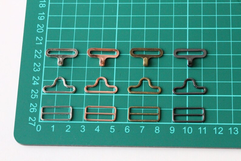 May include: Four sets of metal clasps in silver, copper, gold, and black. Each set includes three different styles: a T-shaped clasp, a D-shaped clasp, and a rectangular clasp.