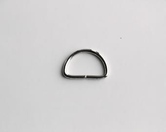 May include: A silver metal D-ring, a type of hardware used for attaching straps, chains, or other accessories.
