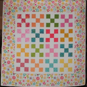 May include: A colorful quilt with a white background and a patchwork design. Each square is a different color and pattern, including pink, green, yellow, orange, blue, and red. The quilt is bordered with a floral print.