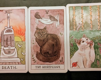 May include: Three tarot cards with watercolor illustrations. The cards feature a vacuum cleaner, a cat with birds, and a cat smelling flowers. The cards are labeled "DEATH.", "THE HIEROPHANT.", and "IV".