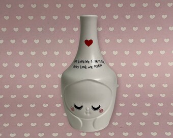Könnte beinhalten: Weiße Keramikvase mit einem Herzdesign und dem Text "The love we give is the only love we keep".
