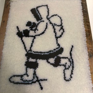 May include: A black and white illustration of a person skiing, framed in a wooden frame. The illustration is made of yarn and is on a white background.