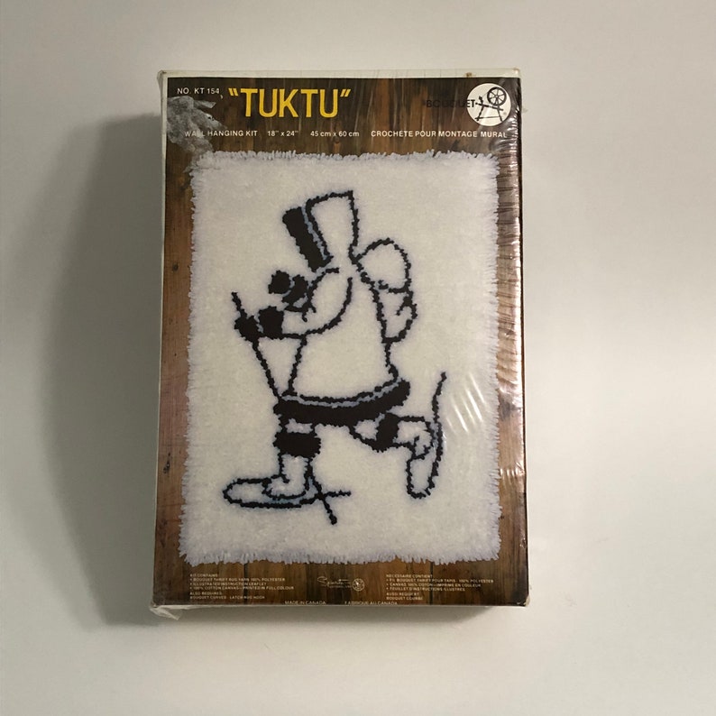 May include: A white craft kit with black and white illustrations of a person cross-country skiing. The kit is labeled "TUKTU" and includes a 18" x 24" wall hanging kit. The kit is made for crocheting.