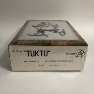 May include: A white box with a black and white image of a person skiing. The box is labeled "TUKTU" and "NO. KT 154". It is a wall hanging kit with the dimensions 18" x 24" or 45 cm x 60 cm.