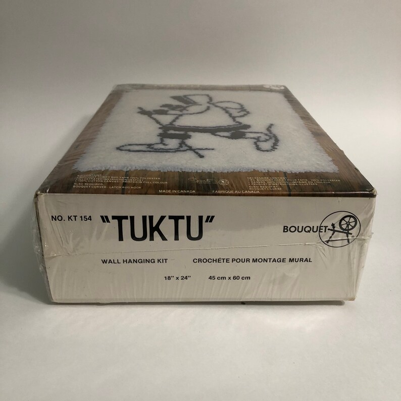 May include: A white box with a black and white image of a person skiing. The box is labeled "TUKTU" and "NO. KT 154". It is a wall hanging kit with the dimensions 18" x 24" or 45 cm x 60 cm.