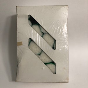 May include: A white box with a clear plastic window showing a package of white and green round items. The items are arranged in a diagonal pattern.