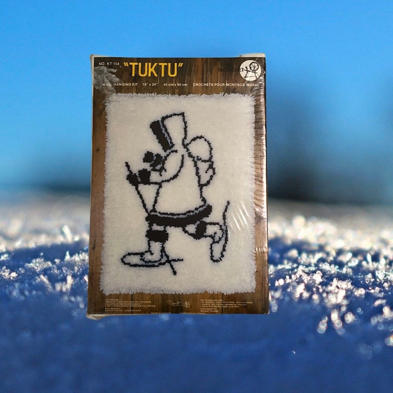 May include: A white crochet kit with a black and white illustration of a person on skis. The kit is labeled "TUKTU" and includes instructions for crocheting a wall hanging. The kit measures 18 x 24 inches.