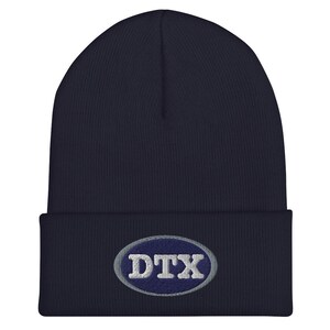 May include: A navy blue knit beanie with a gray oval patch that says "DTX" in white letters.